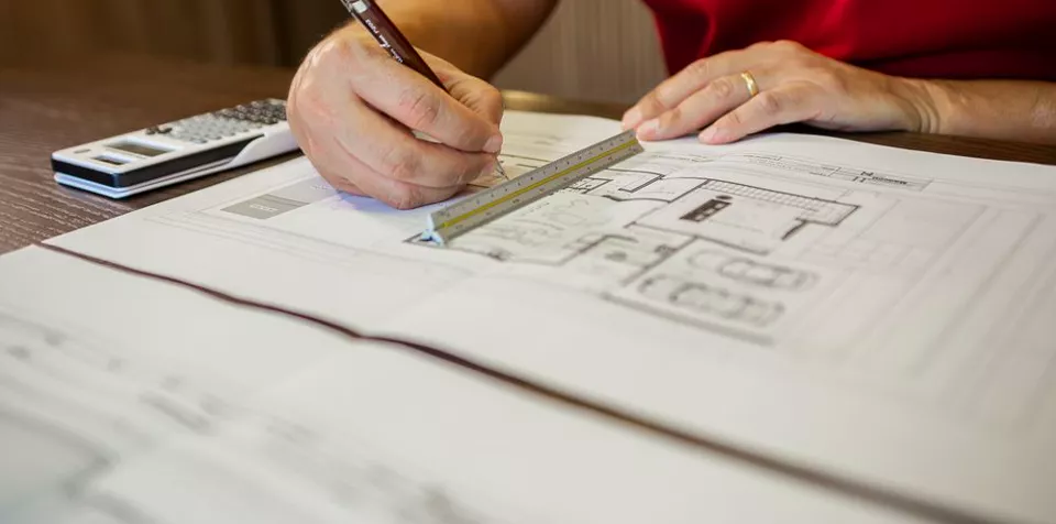 Küchen-Grundriss in der Planung: Hand mit Bleistift und Maßstab auf dem Plan